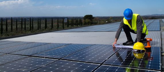 Ein Techniker schaut sich auf einer Solaranlage Pläne an.