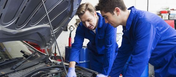 Mechaniker die in den Motorraum eines Autos schauen.