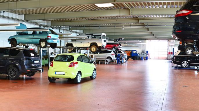 Eine geräumige Garage mit verschiedenen Autos auf Aufzügen, die gewartet werden.