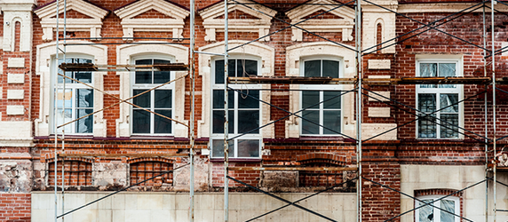 Ein altes Backsteingebäude mit komplizierten architektonischen Details, das gerade restauriert wird und eingerüstet ist.