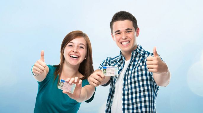 Zwei Personen, ein Mann und eine Frau, zeigen beide mit ihren Händen den Daumen nach oben. Sie halten ihre Ausweise hoch.