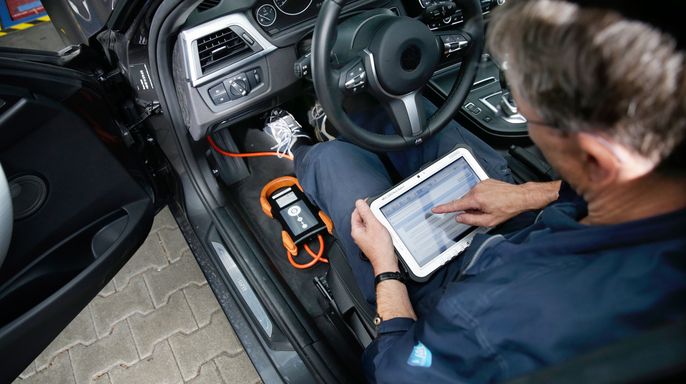 Prüfer in einem Auto bei einer Hauptuntersuchung.