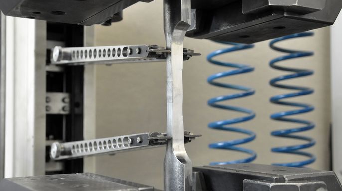 Eine mechanische Vorrichtung mit Metallklammern, einer zentralen Stange und blauen Spiralfedern.