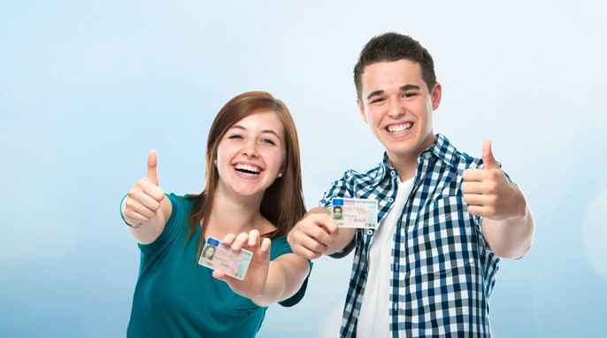 Zwei Personen, ein Mann und eine Frau, zeigen beide mit ihren Händen den Daumen nach oben. Sie halten ihre Ausweise hoch.