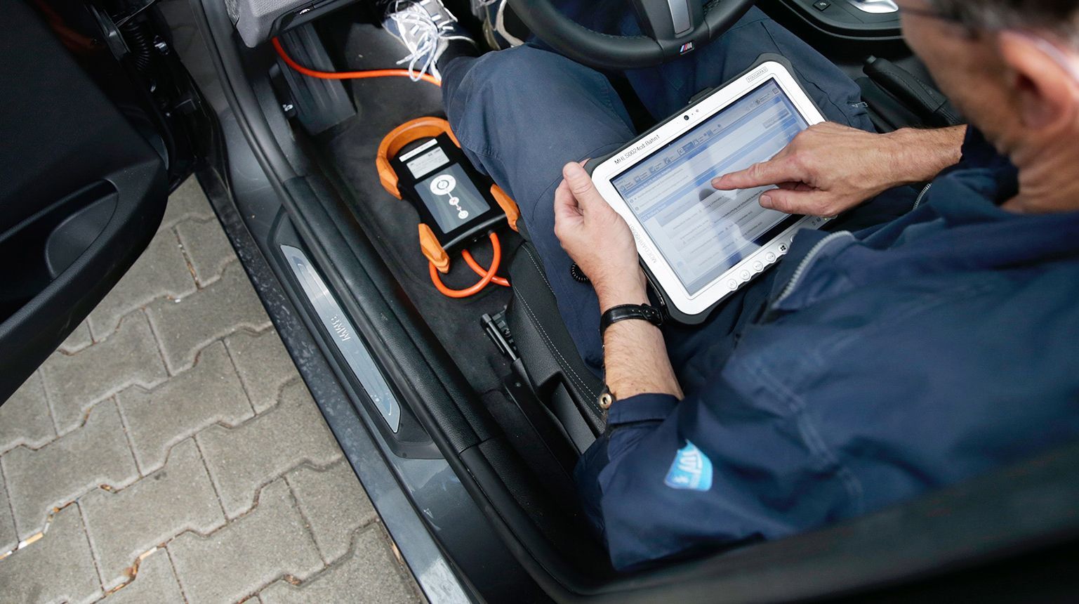 Ein Prüfer in einem Auto bei einer Hauptuntersuchung.