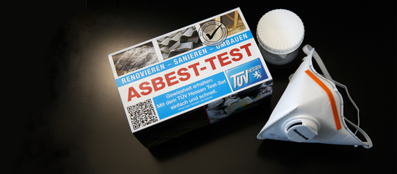 Eine Schachtel mit der Aufschrift "Asbest-Test", in der sich ein Testkit befindet, zusammen mit einer weißen Maske.